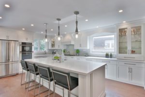 Kitchen remodel with white cabinets and countertops and updated light fixtures.