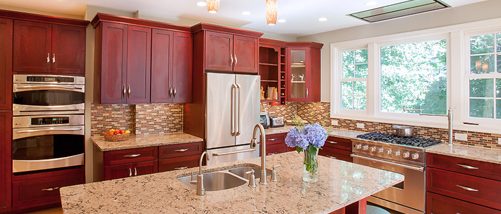 a kitchen with red cabinets and marble counter tops