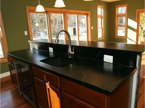 a kitchen with a black counter top and wooden cabinets