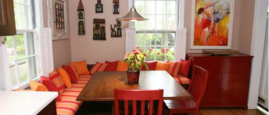 a dining room table with orange and red chairs