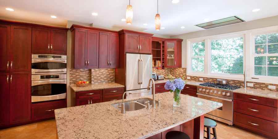 a kitchen with granite counter tops and red cabinets