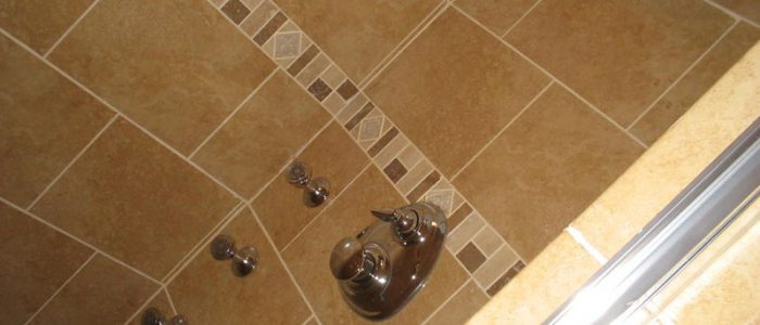 a shower head and hand held shower faucet in a tiled bathroom