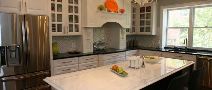 a kitchen with white cabinets and marble counter tops