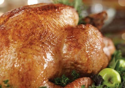 a roasted turkey on a platter with apples and parsley