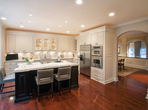 a large kitchen with white cabinets and wooden floors