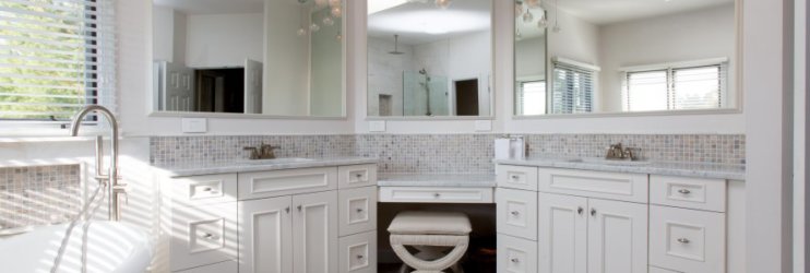 Remodeled bathroom with white cabinetry, dual vanity, and separate soaking tub.