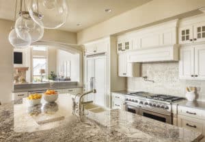 Remodeled kitchen with pendant lighting, white cabinetry, and large kitchen island with built-in sink