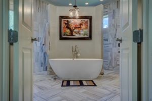 Remodeled bathroom with large white soaking tub and white tile floors.