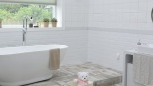 Remodeled bathroom with standing tub and white tile walls.