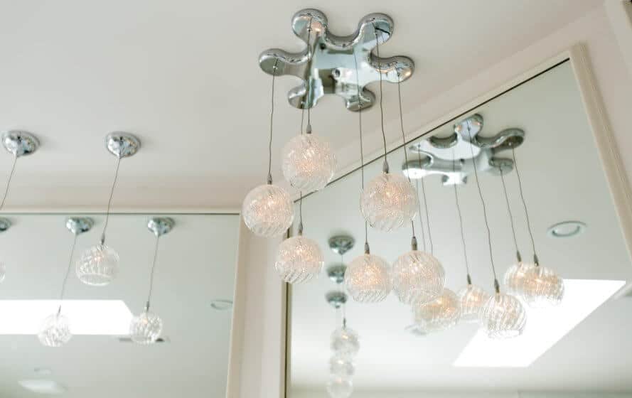 a bathroom with a mirror and lights hanging from the ceiling