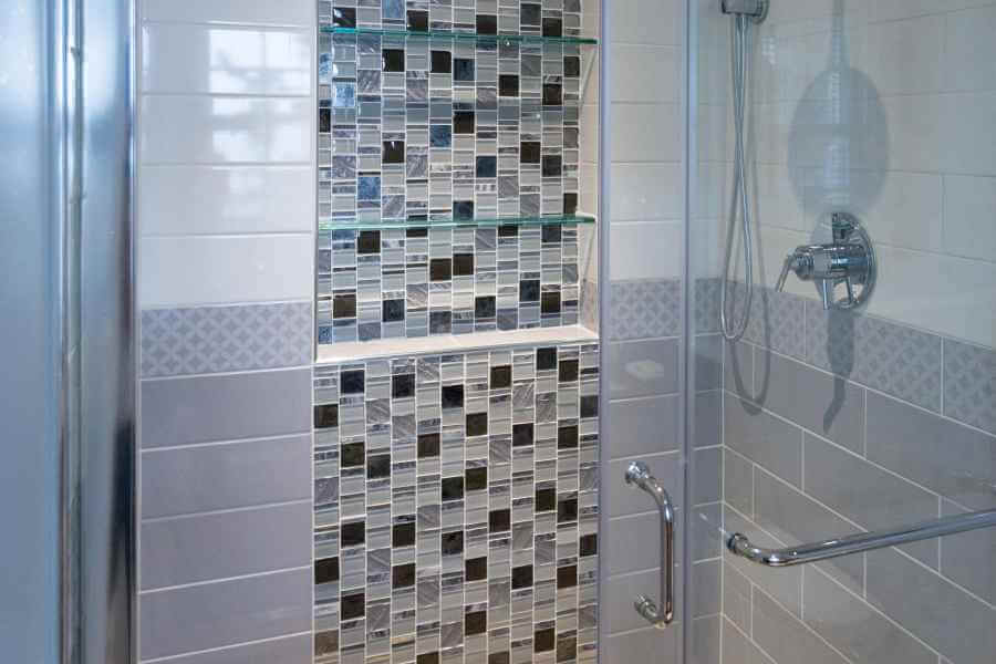 a bathroom with a glass shower door and tiled walls