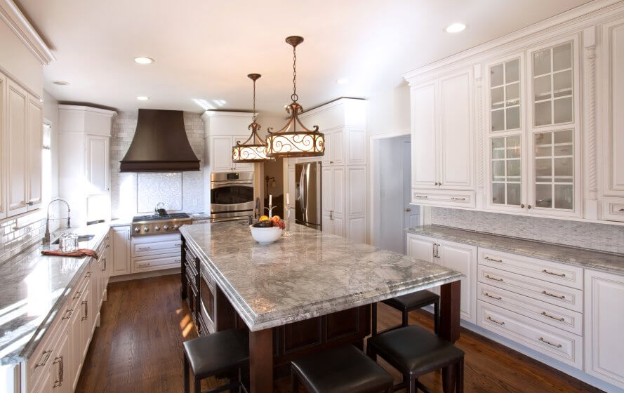 a large kitchen with white cabinets and marble counter tops