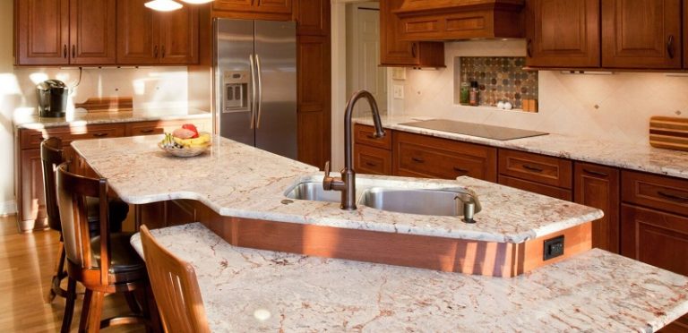 Large two-level kitchen island with white stone countertops, a sink, and seating on one side.