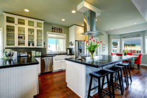 Remodeled kitchen with dark wood flooring, white cabinetry base with dark countertops.