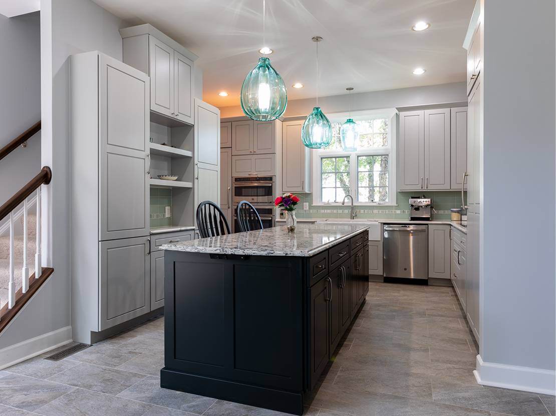 Black kitchen island with a gray granite countertop, white cabinets, and a tile floor.