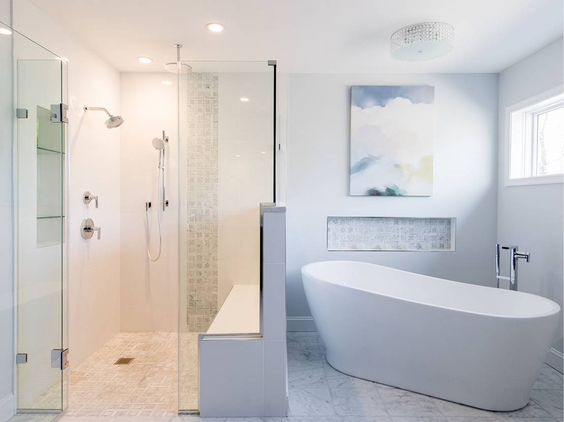 Close up of a bathroom that has a shower with two shower heads and a bathtub.