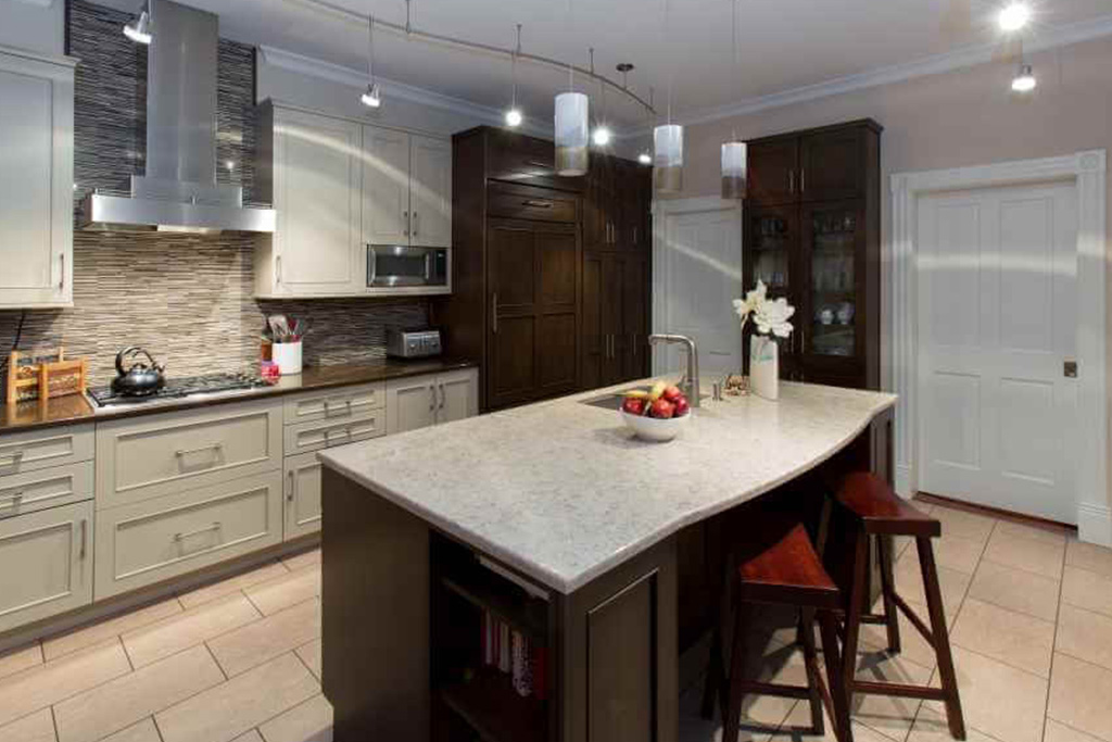 A large gray and dark brown kitchen with a center island. Stone countertops, white tile floor, dark and light cabinets.