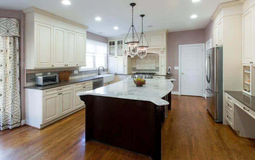 Traditional style kitchen with cream cabinets, dark countertops and a large island with a dark base and white quartz top