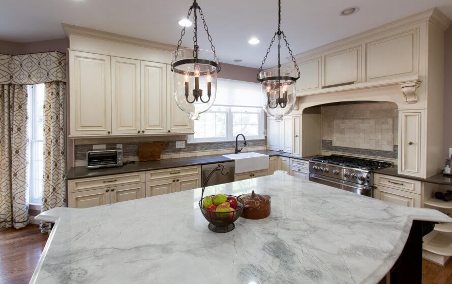 a large kitchen with marble counter tops and white cabinets