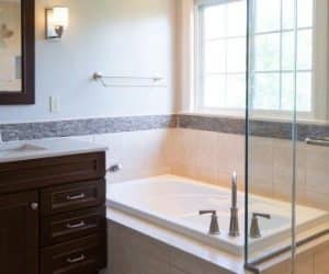 Bathroom with a square, boxed-in bathtub next to a shower and a sink