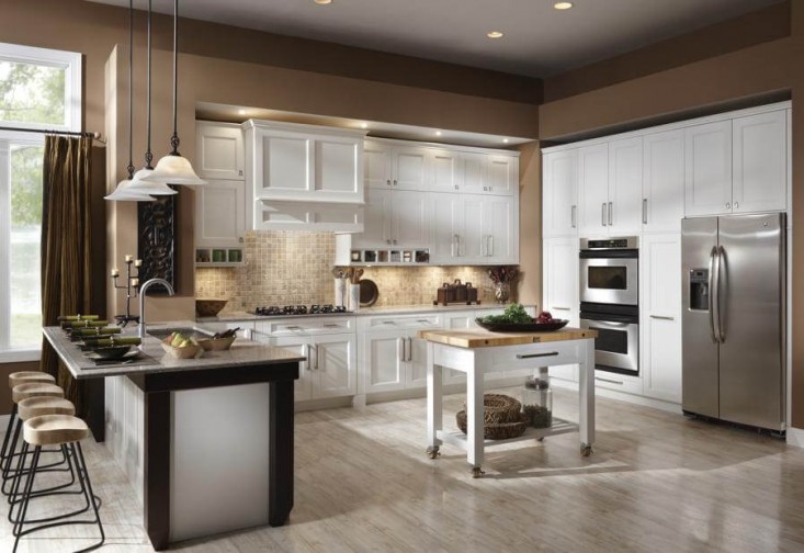 Remodeled kitchen with recessed lighting, stacked built-in ovens, white cabinets, and pendant lighting over the eating area