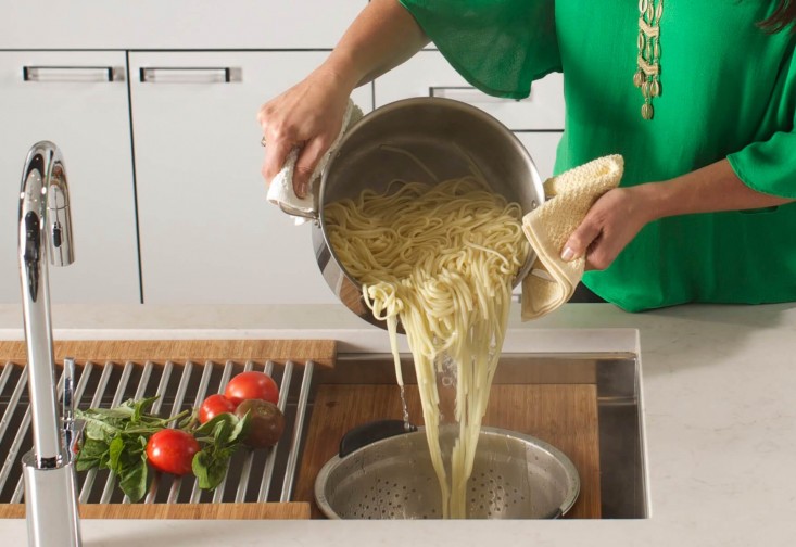 a woman is pouring noodles into a pot
