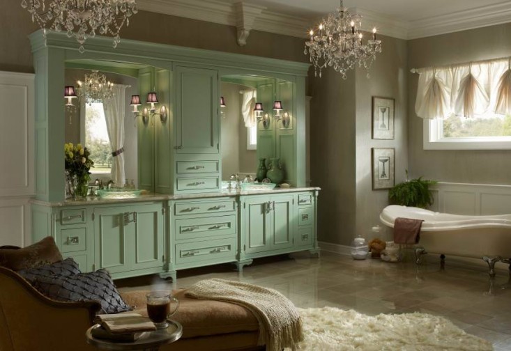 a large bathroom with green cabinets and chandeliers