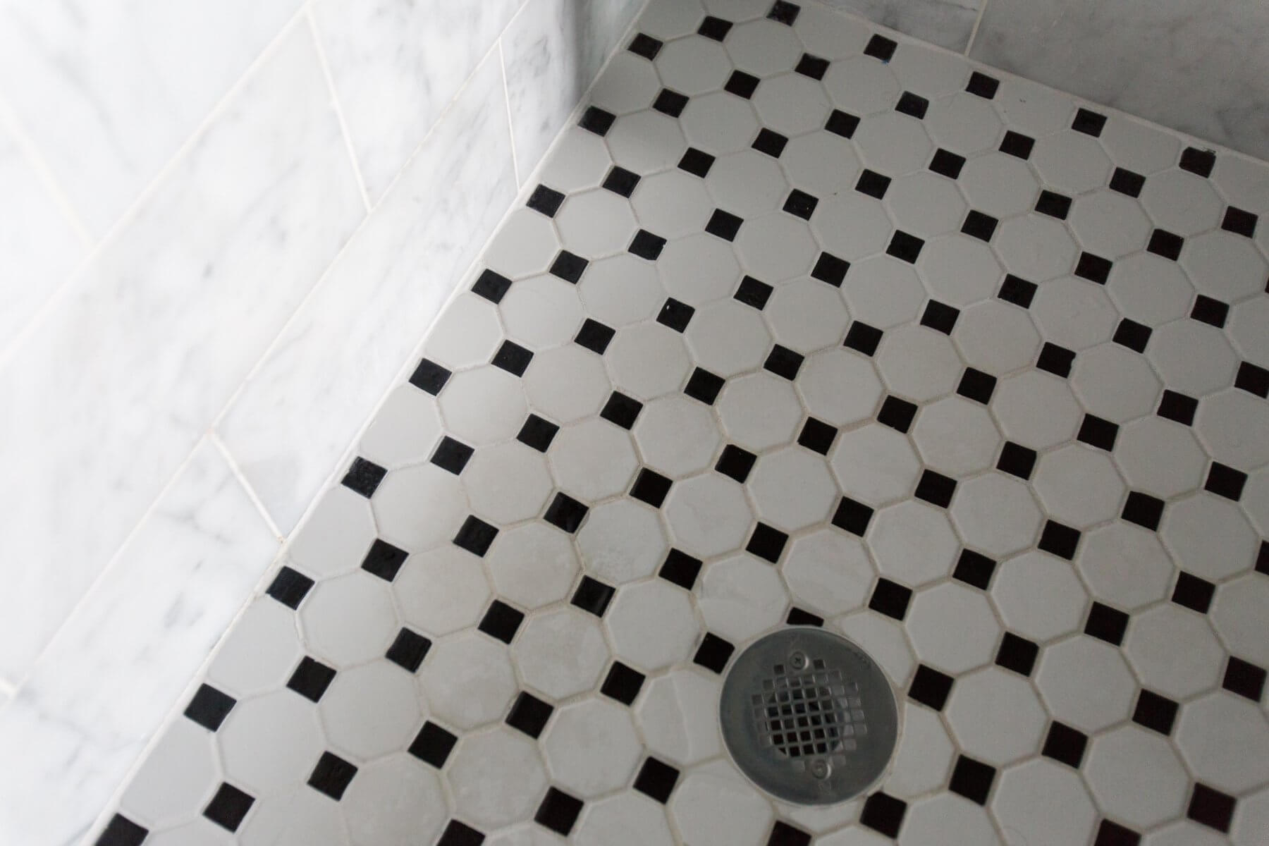 a black and white tiled shower with a drain