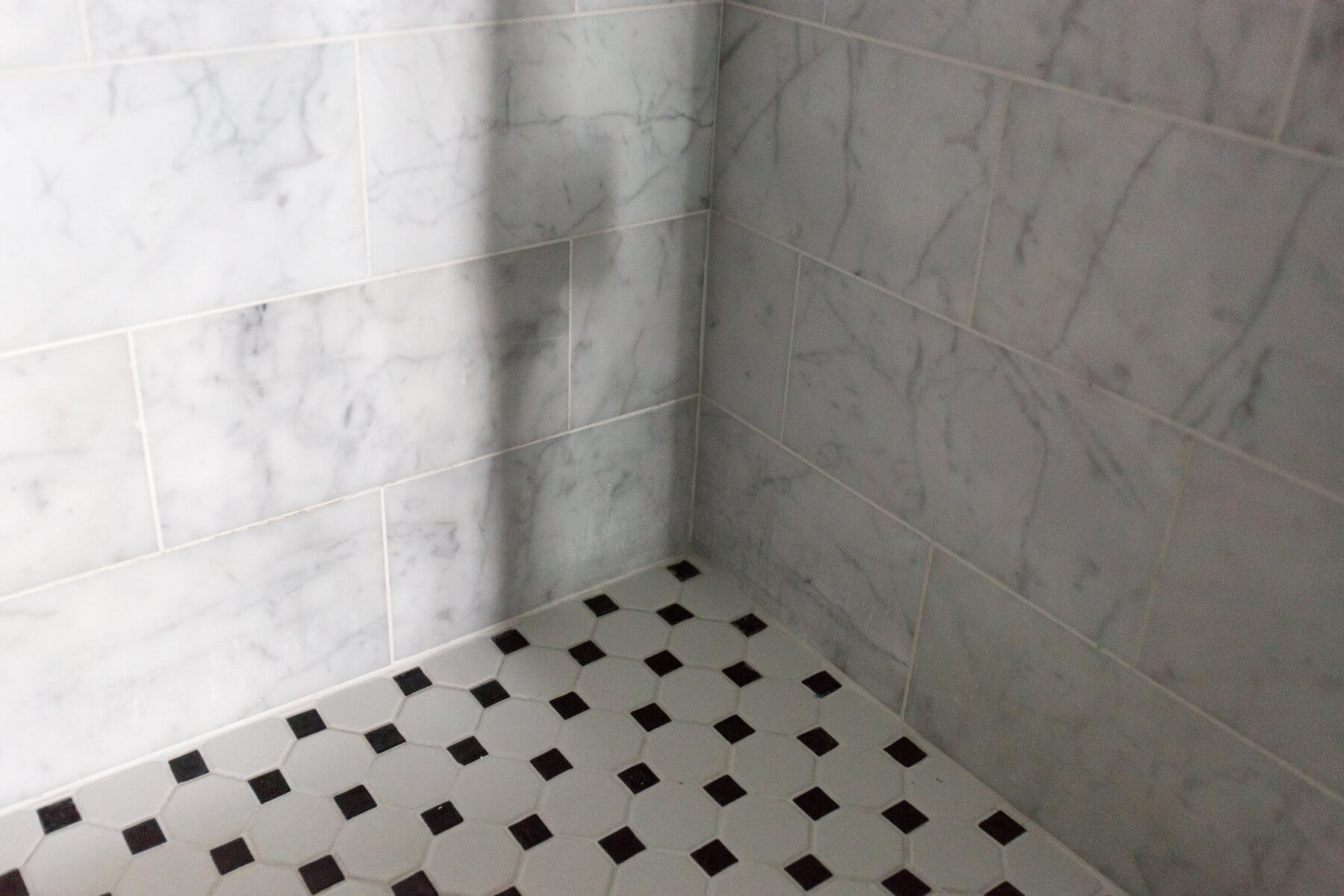 a white tiled bathroom with black and white tiles