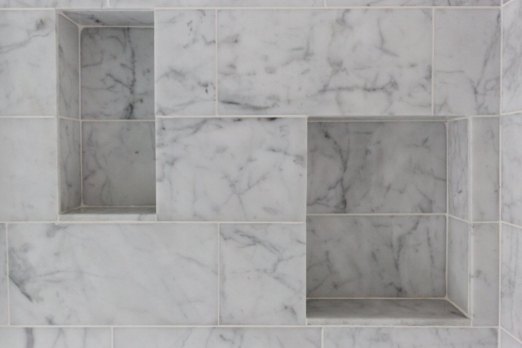 a white marble tiled wall with three niches