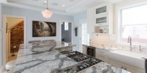 Remodeled kitchen with white cabinets and stone countertops