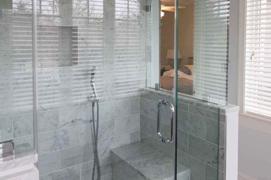 A glass-enclosed walk-in shower next to a window