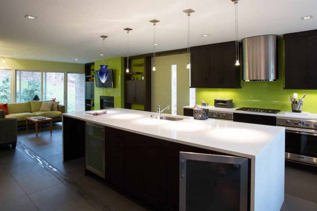 A kosher kitchen with lime green walls and black cabinets with white stone waterfall countertop and stainless steel appliances