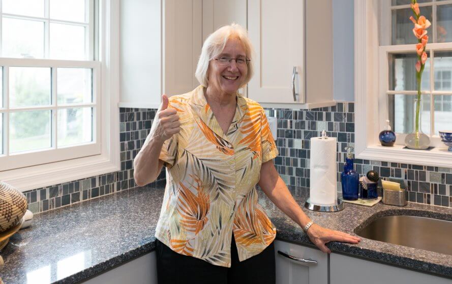 a woman standing in a kitchen giving the thumbs up