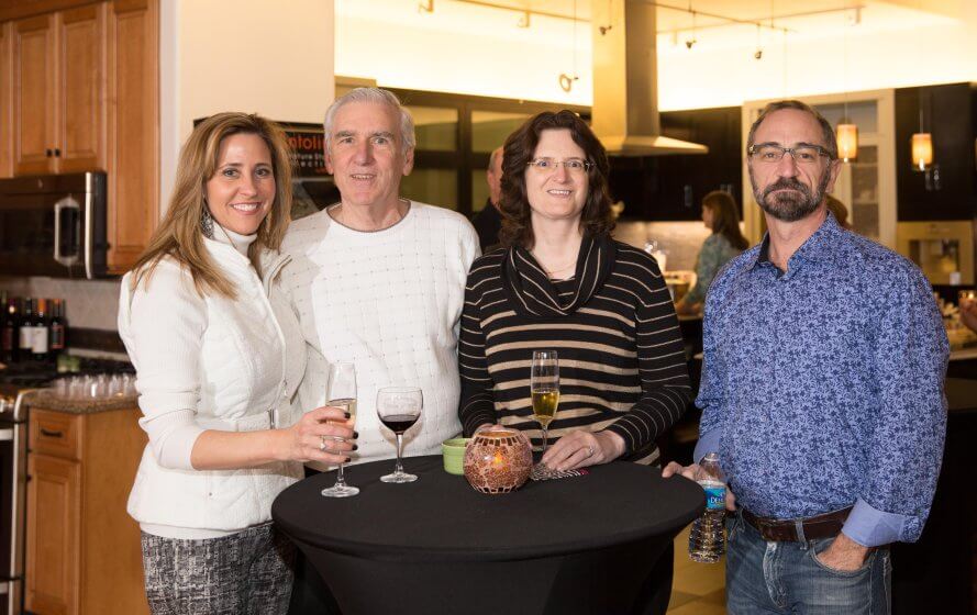 three people standing next to each other holding wine glasses