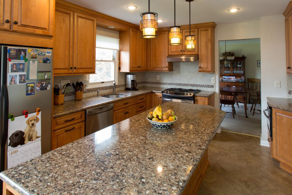 A kitchen with granite countertops and wooden cabinets and a decorated fridge