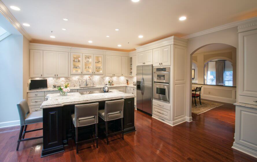 a large kitchen with white cabinets and wooden floors