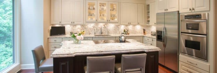 a large kitchen with white cabinets, stone counters, and stainless steel appliances in Potomac