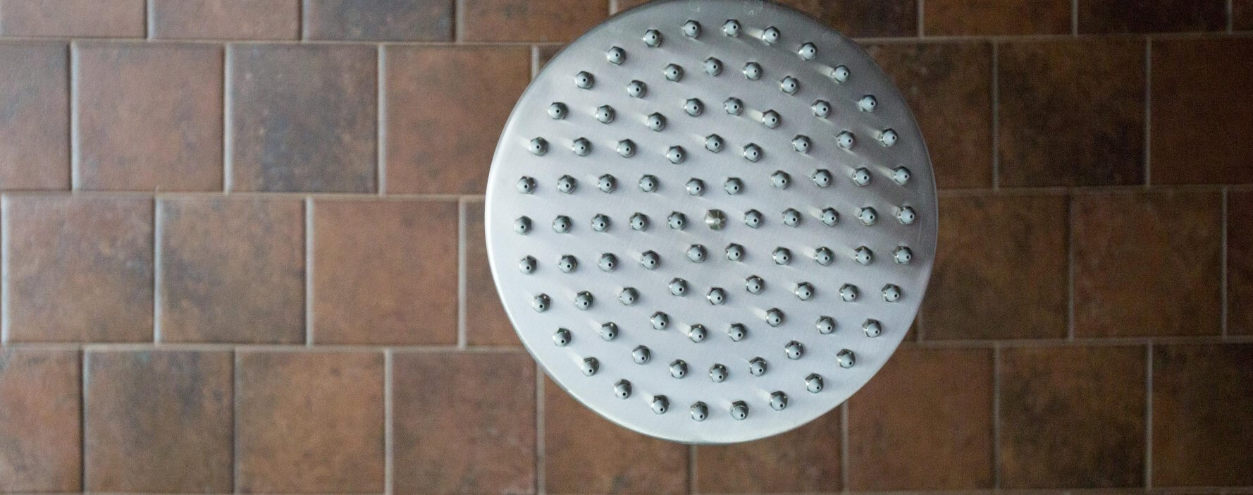 a close up of a shower head on a tiled wall
