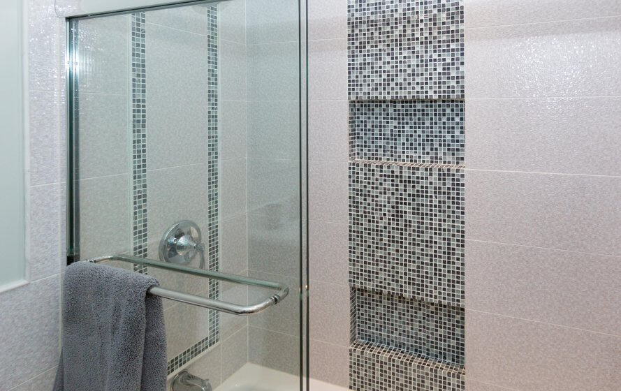 a bathroom with a glass shower door and tiled walls