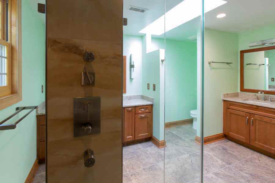 a bathroom with a glass shower door and wooden cabinets