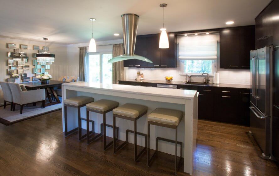 Kitchen remodel with light island and dark cabinets, and pendant and recessed lighting.