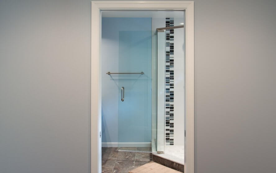 a bathroom with a glass shower door and tiled floor