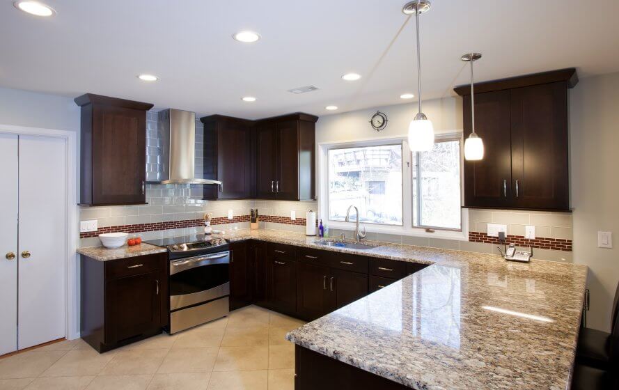 a kitchen with marble counter tops and dark wood cabinets