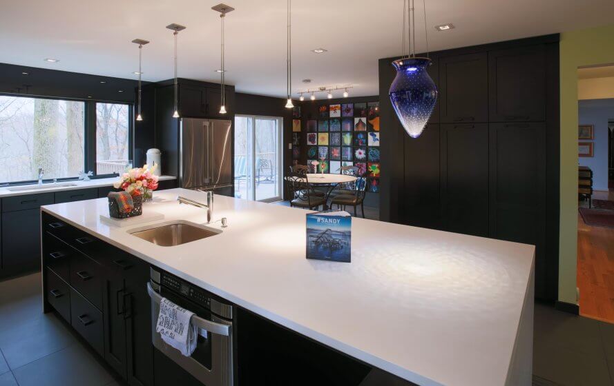 Remodeled kitchen with large island, dark cabinetry and pendant lighting