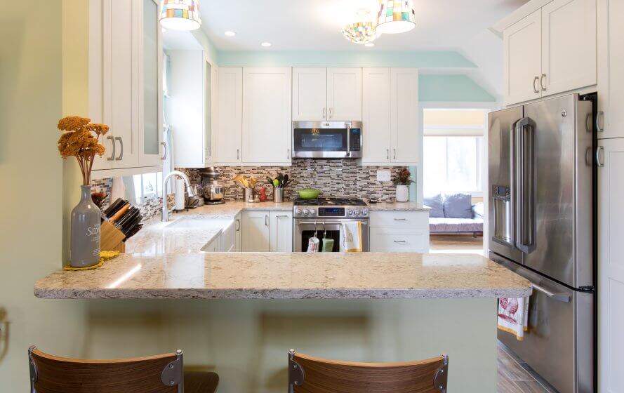 Remodeled small, bright kitchen with white cabinets, peninsula, stone countertops.