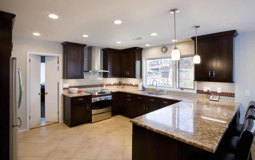 a kitchen with marble counter tops and dark wood cabinets