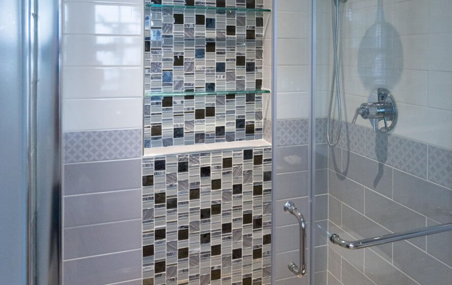 a glass shower door in a tiled bathroom
