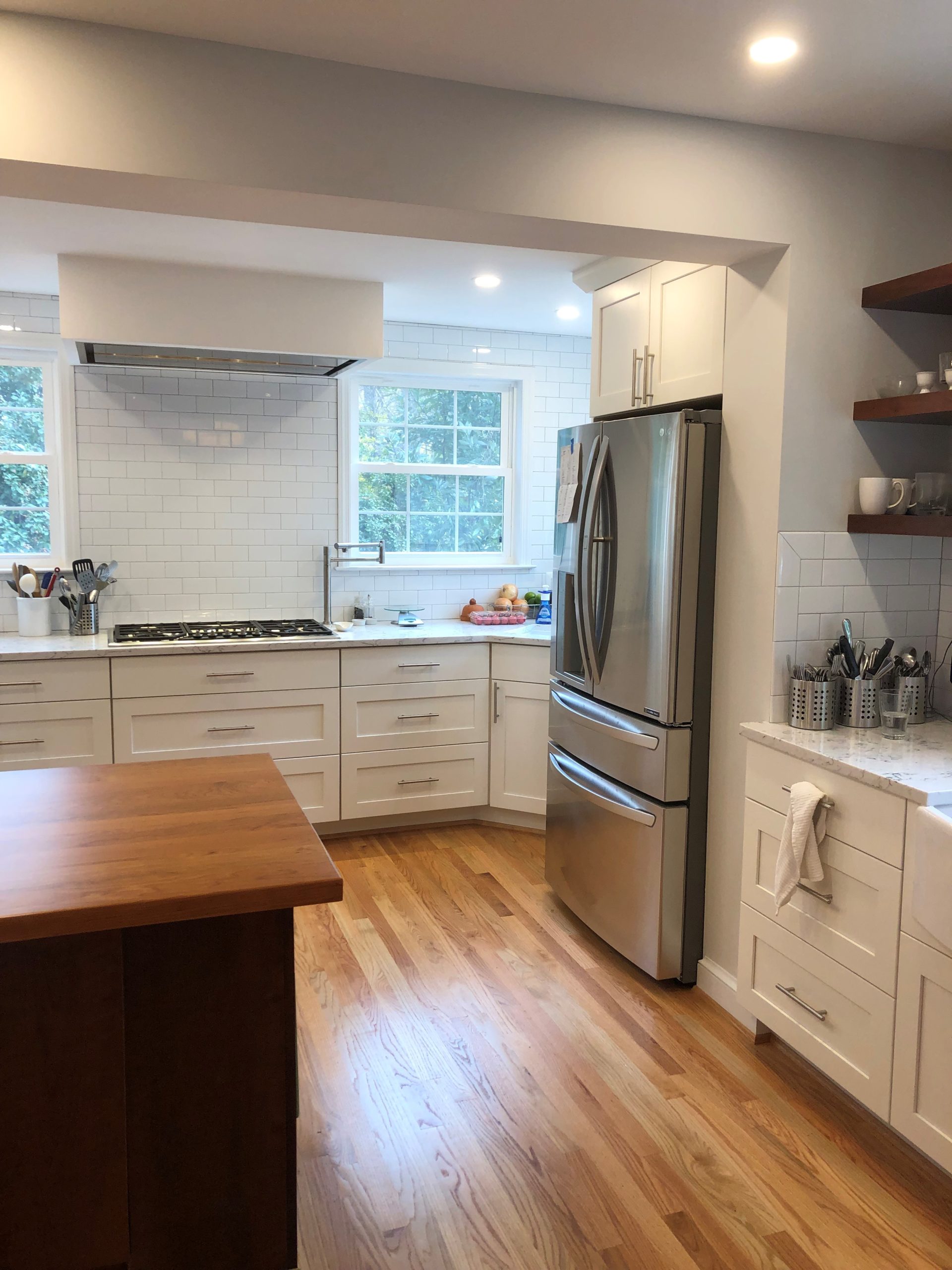 a kitchen with white cabinets, wooden counter, and stainless steel appliances
