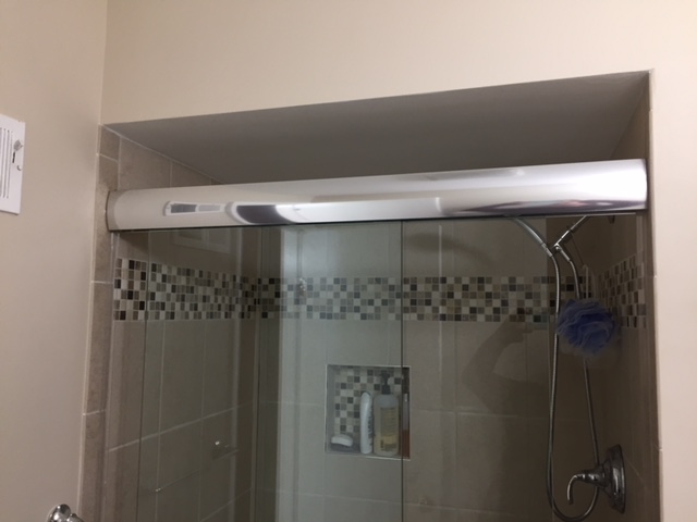 a bathroom with a glass shower door and tiled walls
